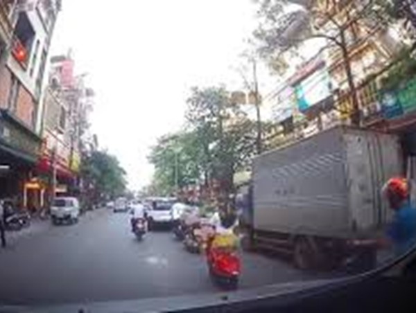 Vừa đi xe vừa nghe điện thoại, người phụ nữ suýt nằm dưới bánh xe ô tô