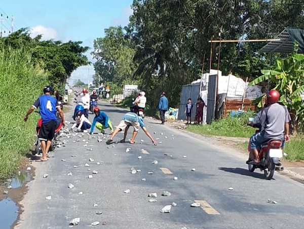 Người dân cùng tài xế xe tải nhặt đá rơi vãi trên quốc lộ