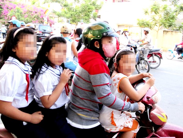 Cha mẹ chở con đầu trần đi qua trước mặt lực lượng tuần tra mà không bị xử phạt
