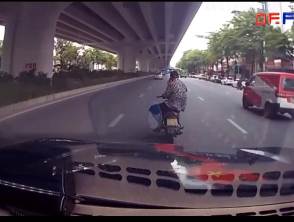 Người đàn ông ngồi vắt vẻo điều khiển xe máy