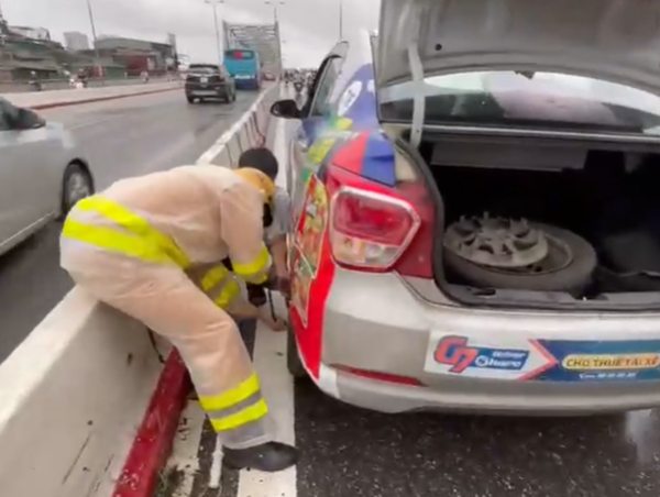 Cảnh sát giao thông Hà Nội giúp người dân thay lốp xe giữa trời mưa