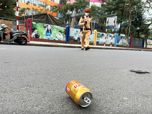 Người đàn ông ngồi trên xe máy ném vội lon bia xuống đường khi gặp cảnh sát giao thông