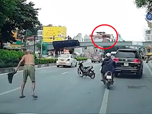 Người đàn ông cởi trần phi dao cắm vào kính ô tô đang chạy trên đường phố Hà Nội
