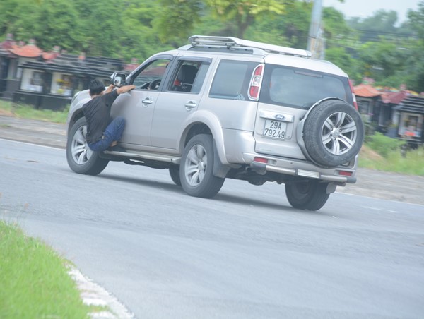 Người đàn ông đu cửa ô tô “biểu diễn xiếc” trên đường phố