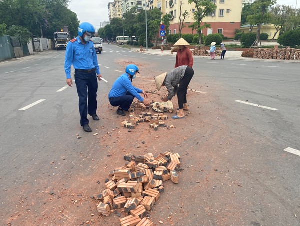 Thanh tra giao thông cùng người dân dọn hàng trăm viên gạch rơi vãi ra đường