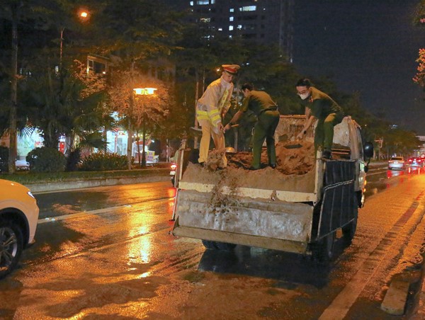 Cảnh sát giao thông đội mưa trải cát thấm dầu trên đường Lê Trọng Tấn