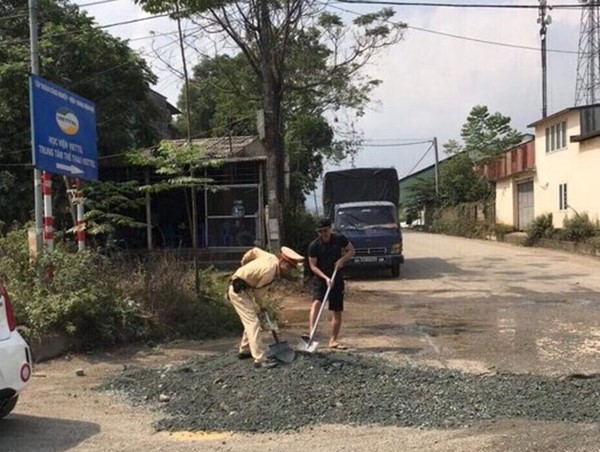 Cảnh sát giao thông san lấp 'ổ trâu' đảm bảo cho người dân đi lại an toàn