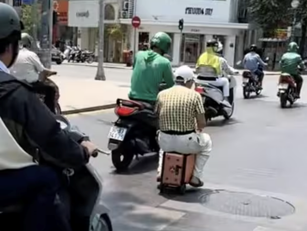 Người đàn ông ngồi vali điện lưu thông trên đường ở TP Hồ Chí Minh