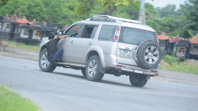 Người đàn ông đu cửa ô tô “biểu diễn xiếc” trên đường phố