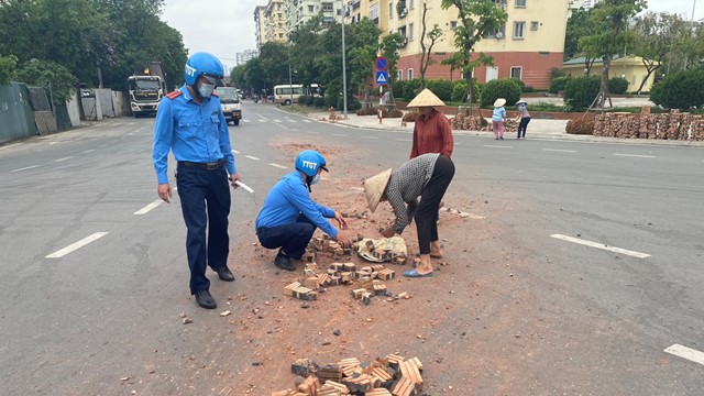 Thanh tra giao thông cùng người dân dọn hàng trăm viên gạch rơi vãi ra đường